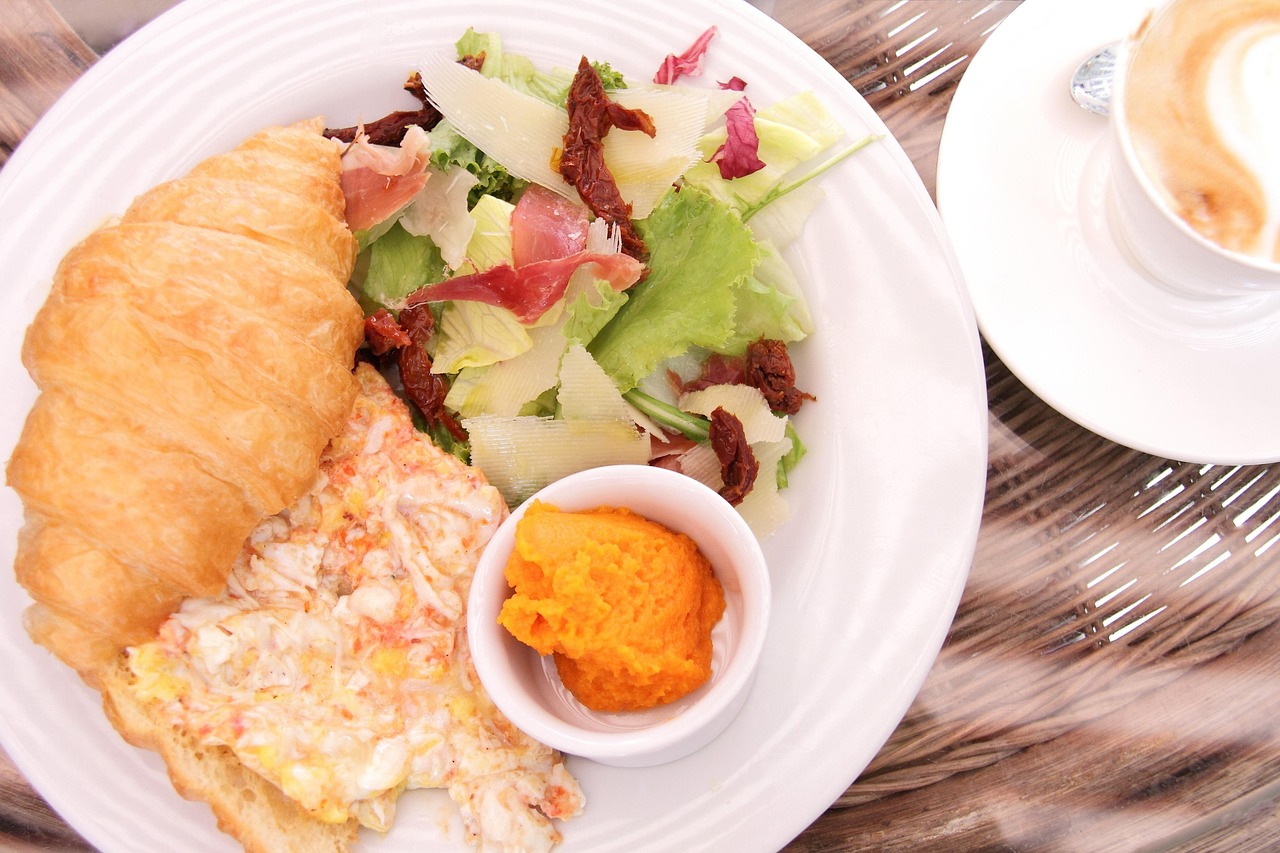 Colazione salata con uova e verdure accanto a una colazione dolce con pancake e frutta.